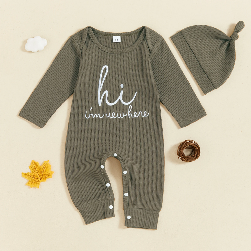 Grön babyoverall med broderad text och knutmössa, platt lagd